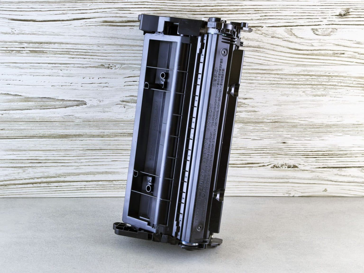 Black printer toner cartridge photographed from the side